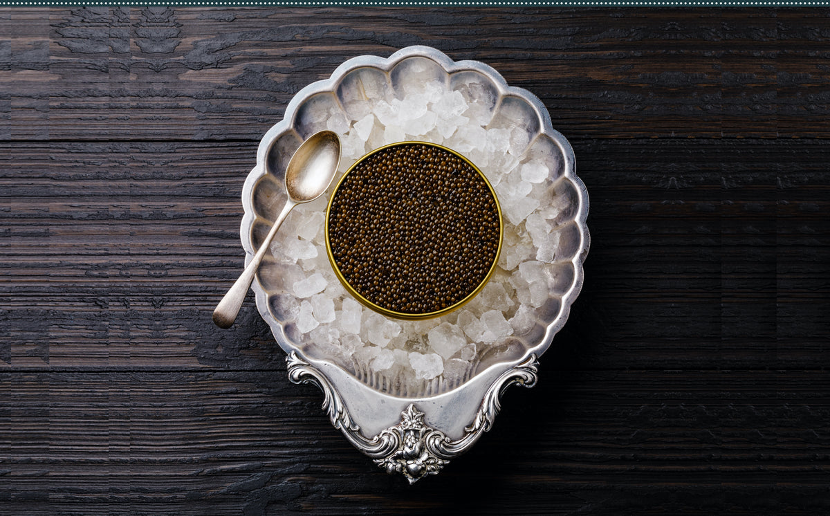 an opened petrusco caviar tin into a silver ice box on a wooden table