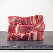 Load image into Gallery viewer, Stack of Grass-Fed Australian Wagyu Ribeye MS 8-9 on a slate surface with a white background
