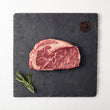 Load image into Gallery viewer, Grass-Fed Australian Wagyu Ribeye MS 8-9 on a slate board with rosemary and peppercorns
