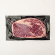 Load image into Gallery viewer, Grass-Fed Australian Wagyu Ribeye MS 8-9 on a black plastic wrap against a white background
