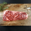 Load image into Gallery viewer, Grass Fed Australian Wagyu Striploin on a wooden cutting board with rosemary
