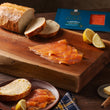 Load image into Gallery viewer, Thinly sliced smoked salmon on a wooden cutting board with sourdough bread, lemon wedges, butter, and Loch Duart packaging
