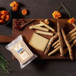 Load image into Gallery viewer, Assorted cheese and crackers on a wooden board with dried apricots and flowers.
