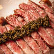 Load image into Gallery viewer, A close up of a row of black caviar on a cut up steak 
