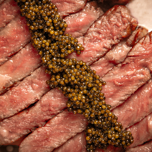 A close up of black caviar on a cut steak