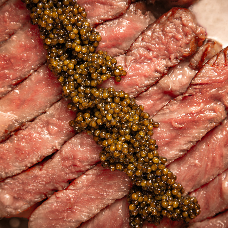 A close up of black caviar on a cut steak