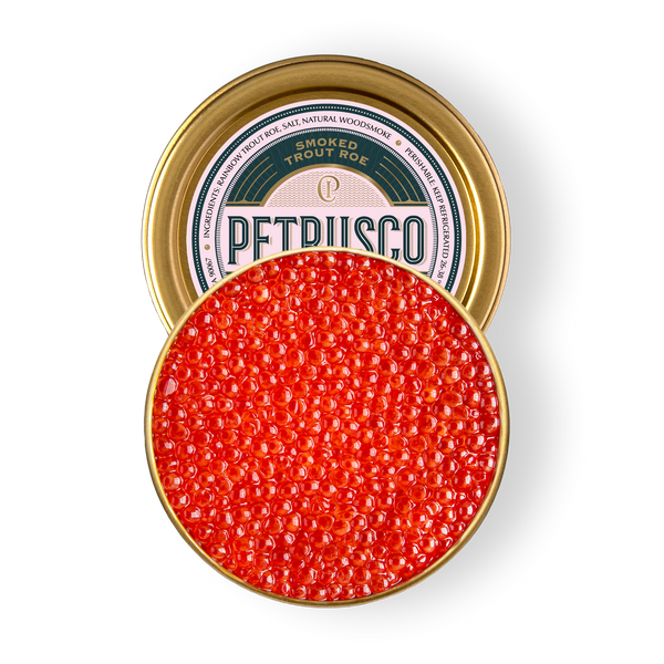 Overhead view of vibrant red smoked trout roe in an open gold tin.