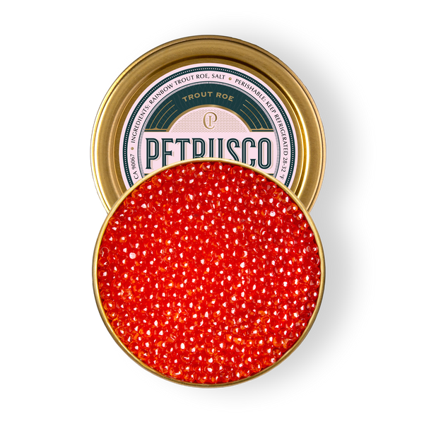 Overhead view of vibrant red rainbow trout roe in an open gold tin.
