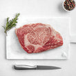 Load image into Gallery viewer, Petrusco Caviar fresh Japanese A5 Wagyu Ribeye Steak on a marble cutting board with herbs, fresh pepper, and salt.
