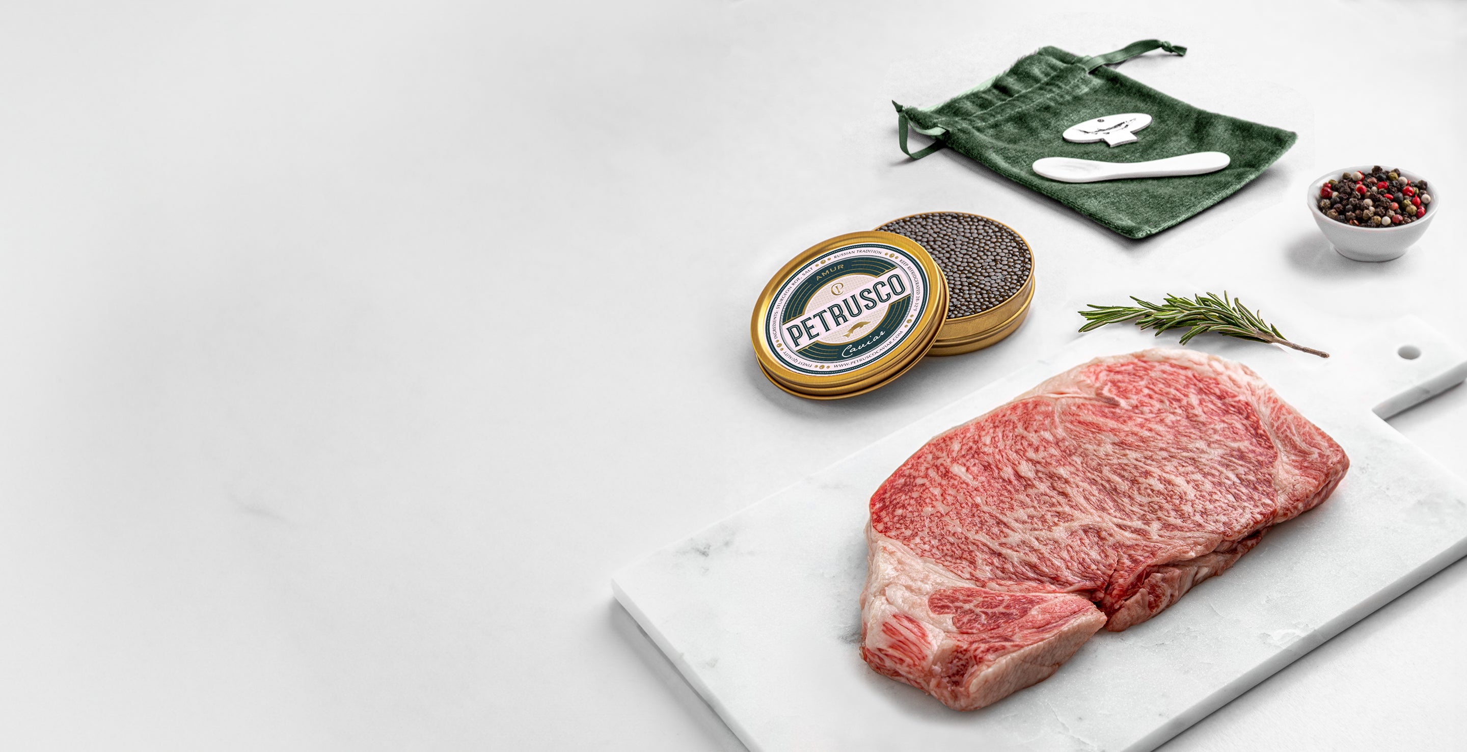A gold tin of black Amur Petrusco caviar in front of meat 