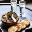 Load image into Gallery viewer, Close-up of a blini topped with crème fraîche and a generous spoonful of golden Royal Ossetra caviar pearls.
