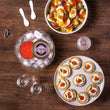 Load image into Gallery viewer, Overhead spread of Petrusco Smoked Trout Roe on ice alongside blini topped with crème fraîche, dill, and roe, with a potato egg salad and vodka glasses on a wooden table

